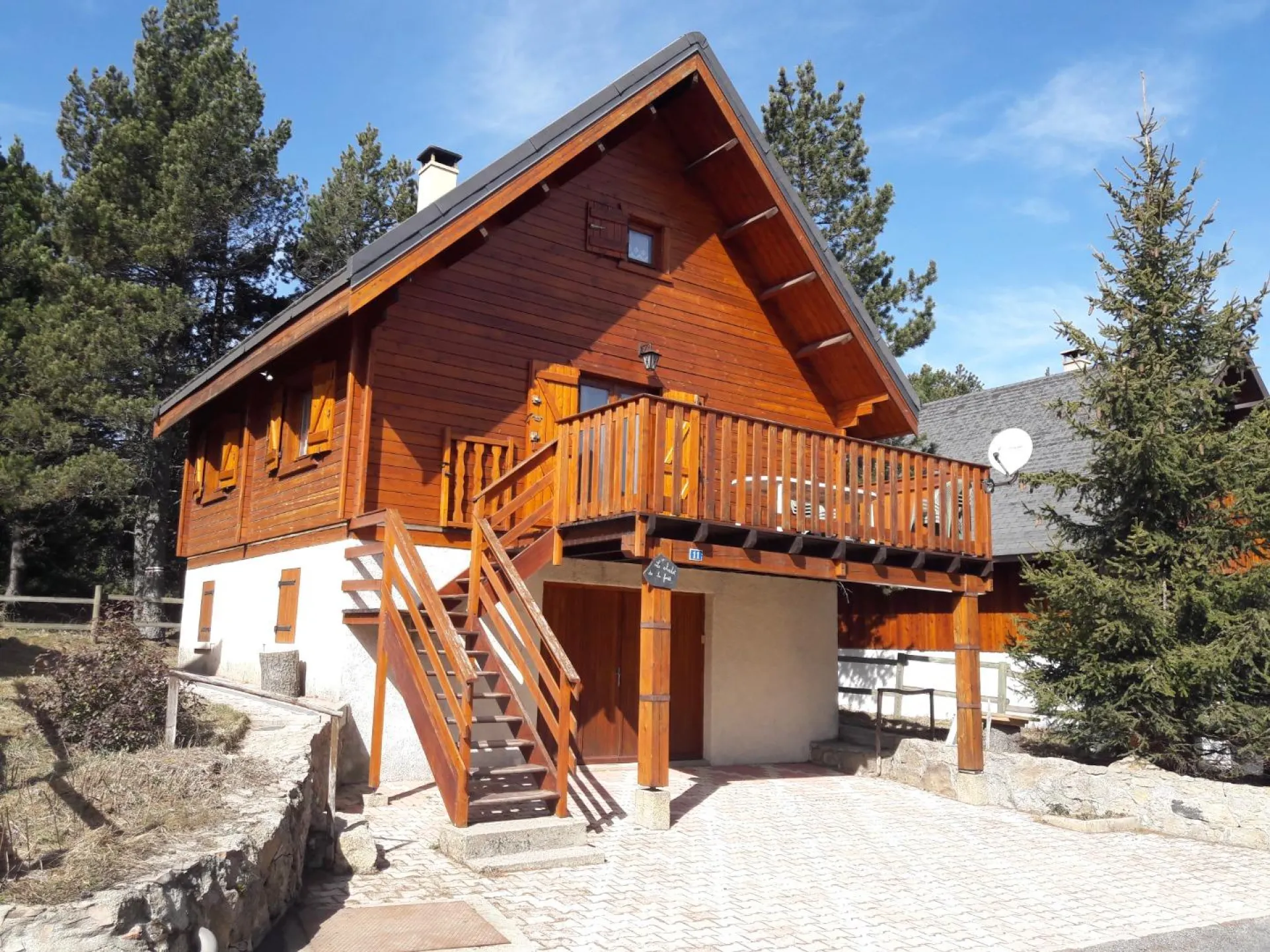 Vue du chalet (été) avec 2 places privatives - accès par escalier vers terrasse et/ou porte garage rez de jardin - parcelle clôturée avec accès direct dans la forêt par portillon derrière le chalet