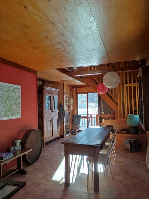 A large, bright dining room with a farmhouse table for 8 to 10 people and an antique wardrobe with all the crockery. The kitchen is adjoining. At the back on the right, the stairs to access the mezzanine