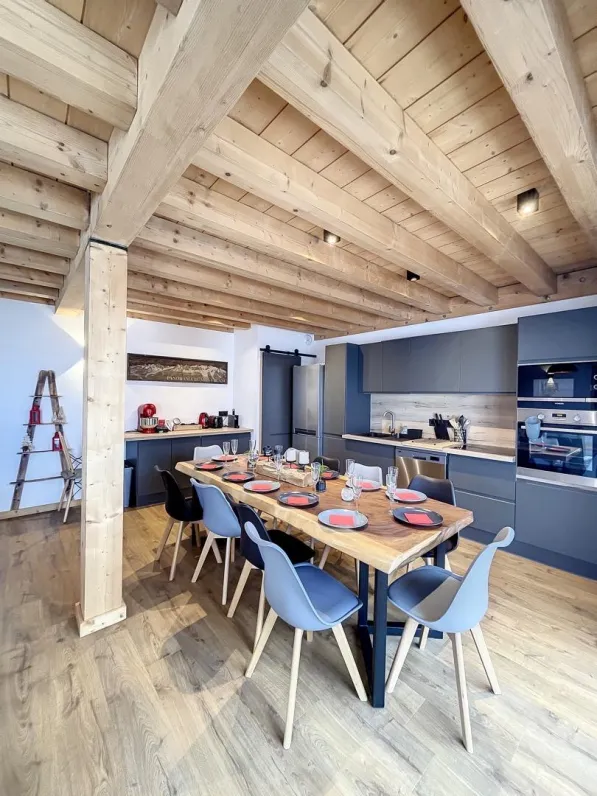 Dining room with a wooden table and a fully equiped kitchen.
