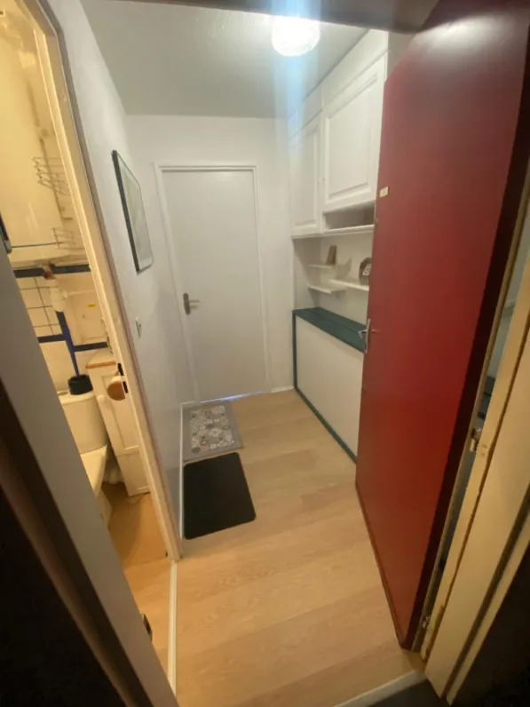 Vue de l'entrée avec un lit d'appoint, donnant sur la salle de bain et la pièce à vivre.