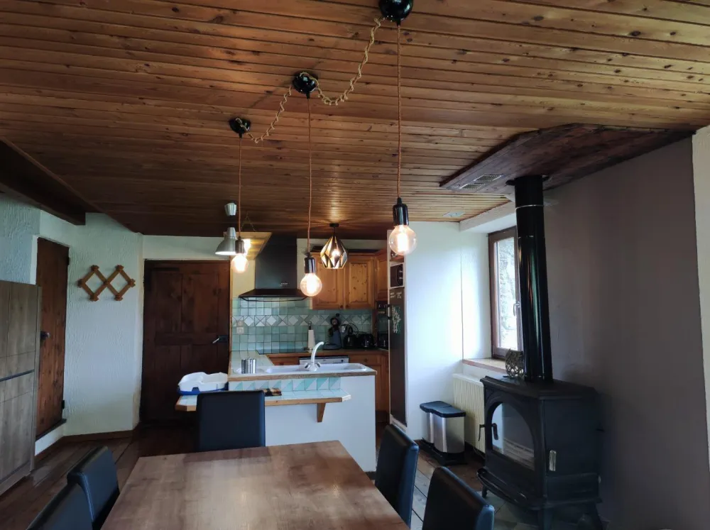Table à manger, poêle à bois et cuisine dans le fond