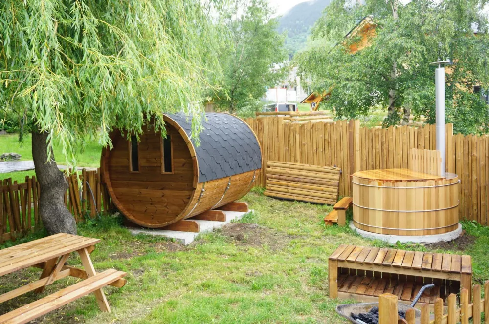 jardin avec table de pique-nique, sauna tonneau acessible en libre-service (compris dans le prix) pour 6 personnes.
On voit un bain nordique sur la photo mais suite à de mauvaises utilisations, on a du le condamner.Il n'est donc plus utilisable.
