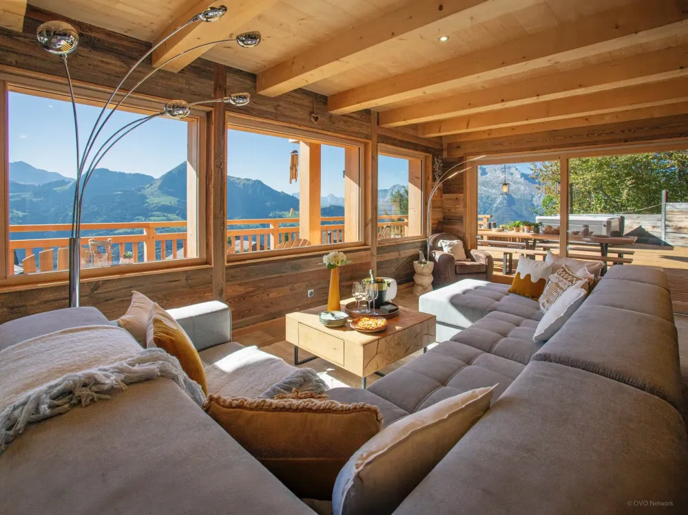 L’élégance alpine dans toute sa splendeur : un salon spacieux, baigné de soleil, offrant une vue exceptionnelle sur les montagnes. Le cœur du chalet, pensé pour le bien-être et le luxe.;