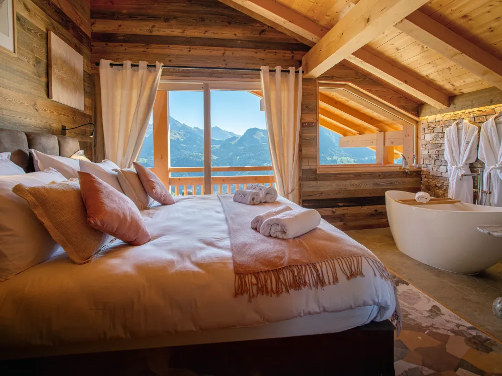 Suite parentale élégante avec baignoire et vue imprenable sur les sommets. Un cocon de luxe pour des moments de pure détente.