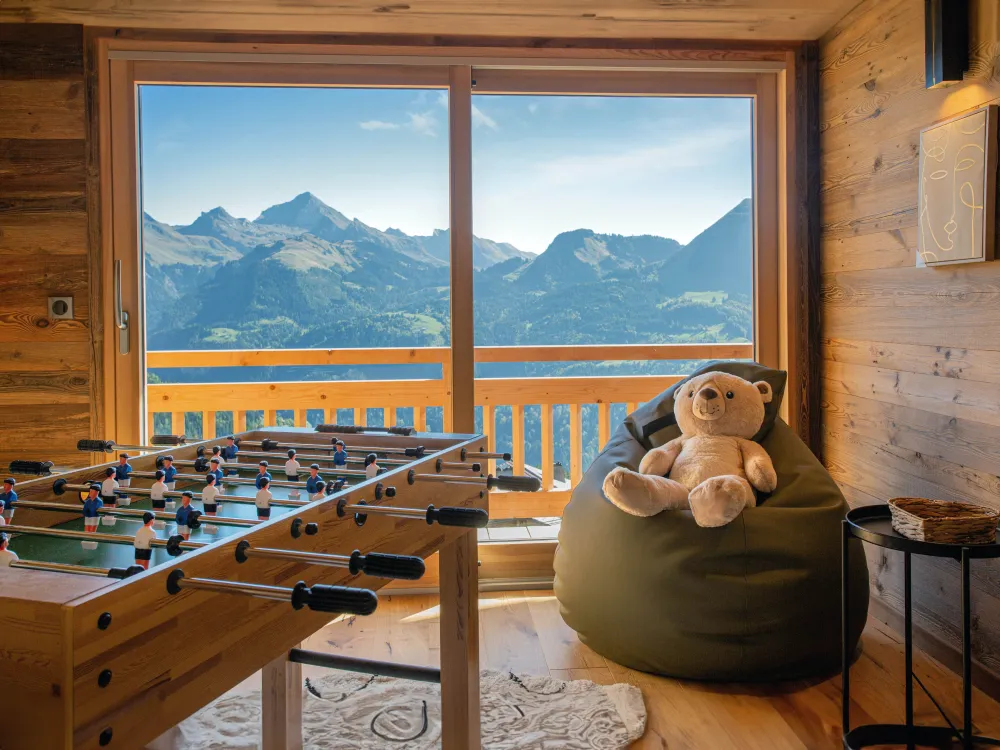 Espace détente avec baby-foot et vue ouverte sur les Alpes. Un lieu chaleureux où petits et grands partagent des moments de plaisir face aux montagnes.