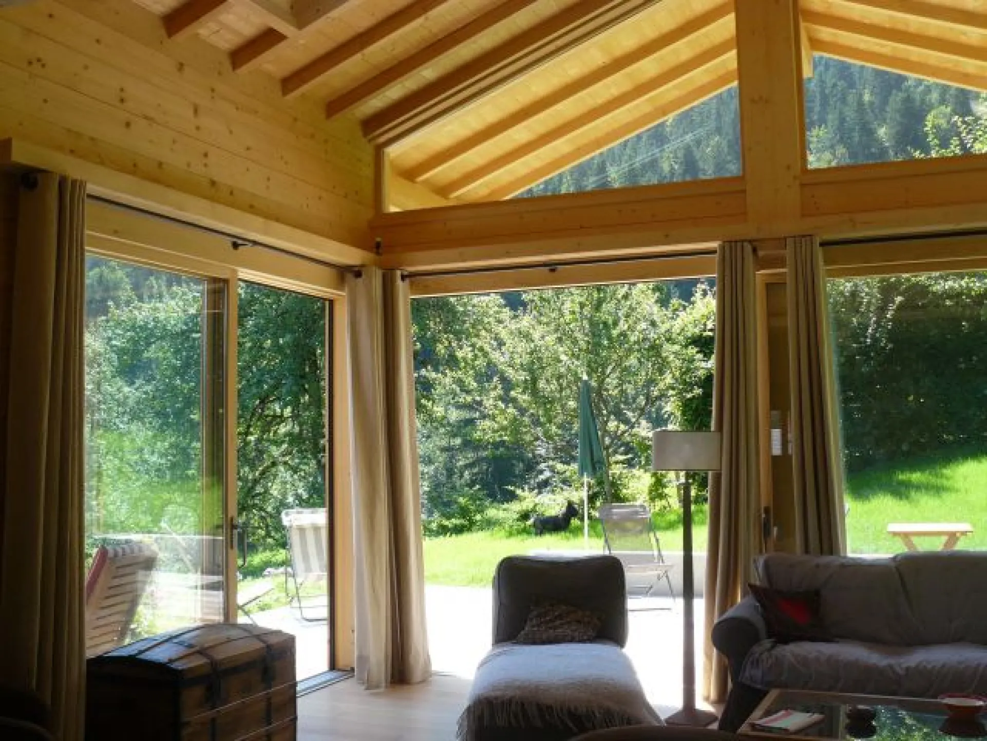 Une partie du salon,avec grandes baies vitrées ouvrant sur une grande terrasse en bois, exposée est-sud-ouest