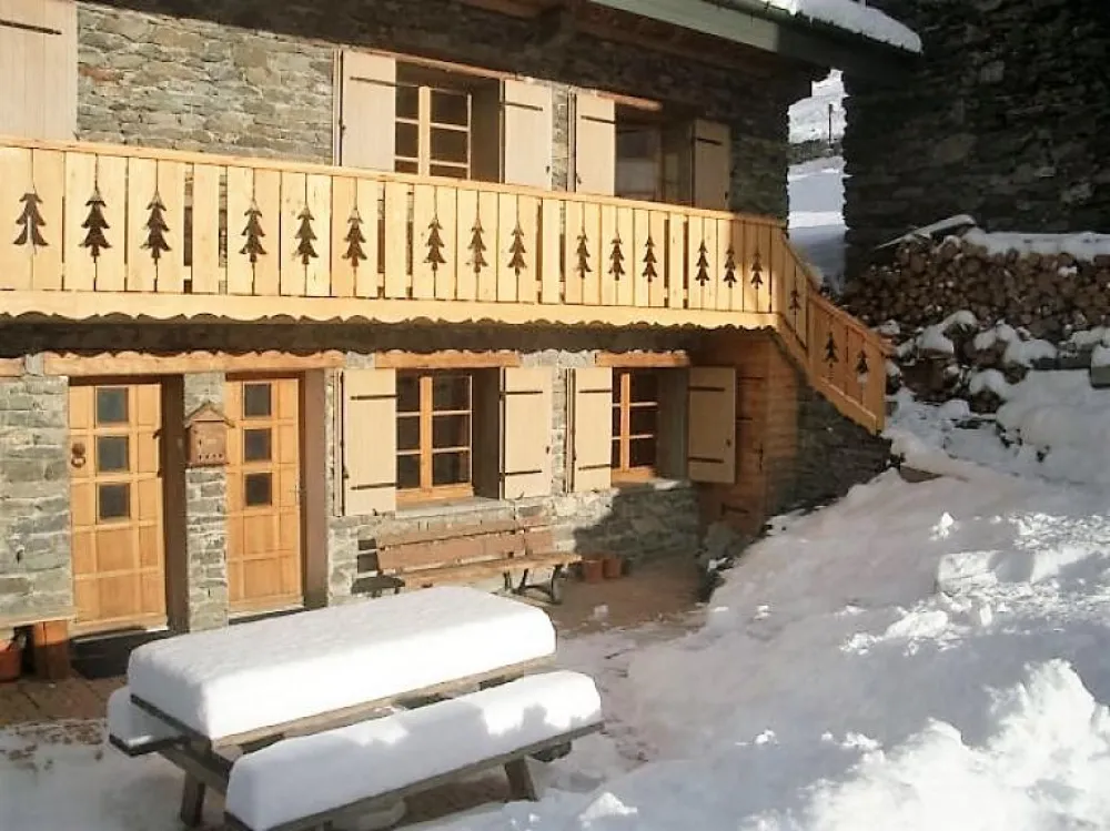 La terrasse avec table et bancs au soleil, l'entrée de l'appartement porte de droite