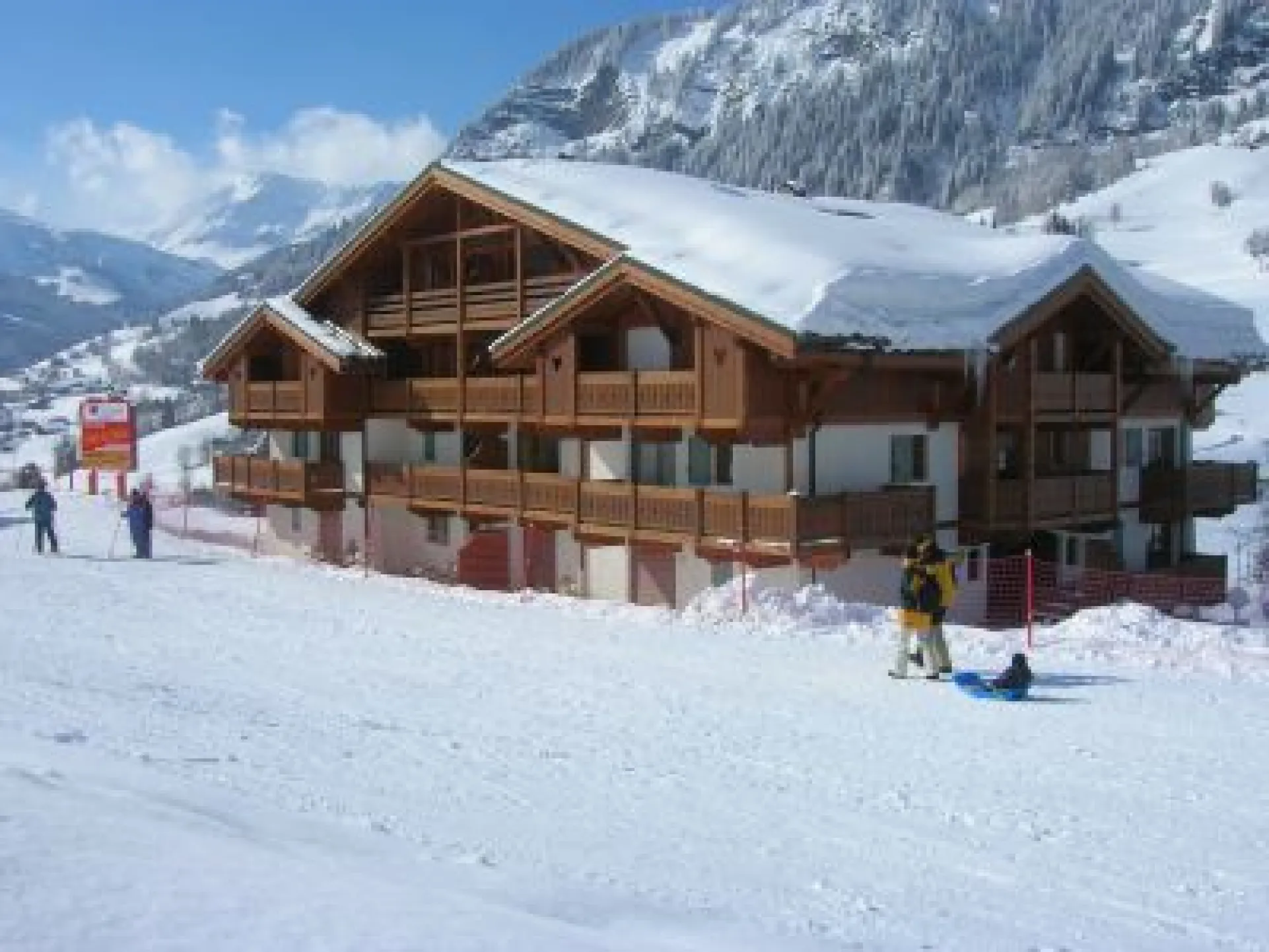 Chalet : vue depuis les pistes. Appartement situé au dernier étage (balcon de gauche exposé sud/sud est). A l'arrière plan la barrière des Aravis vers La Giettaz et Annecy.
