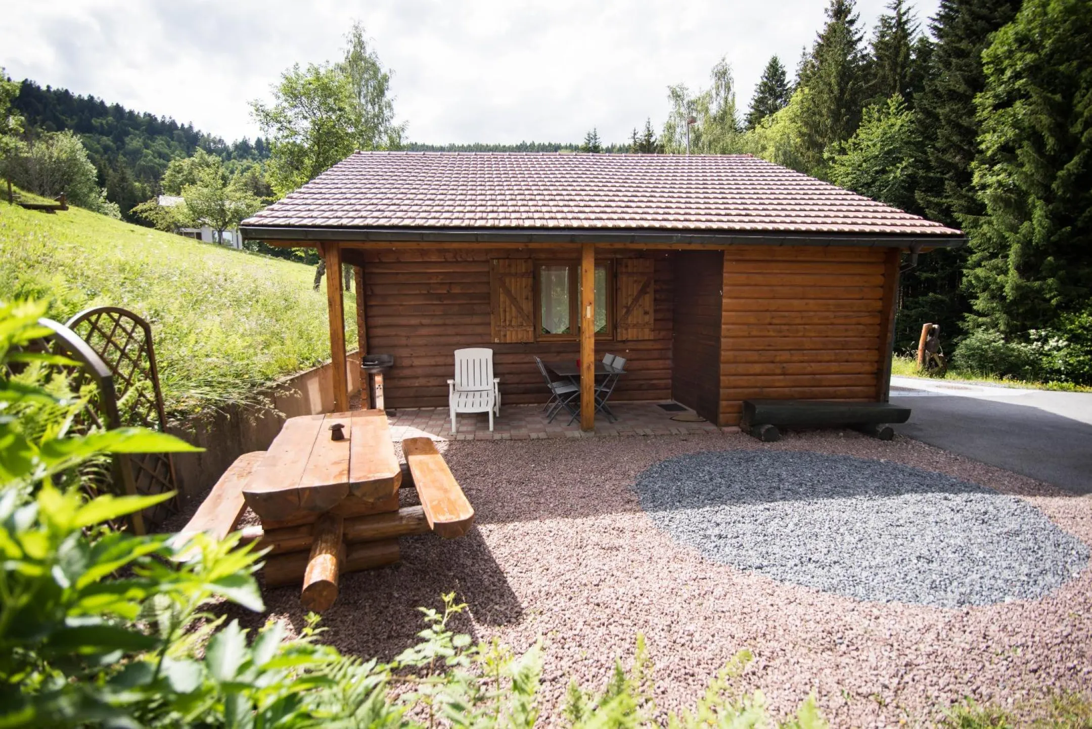 Chalet avec terrasse couverte et salon de jardin (vue de face)