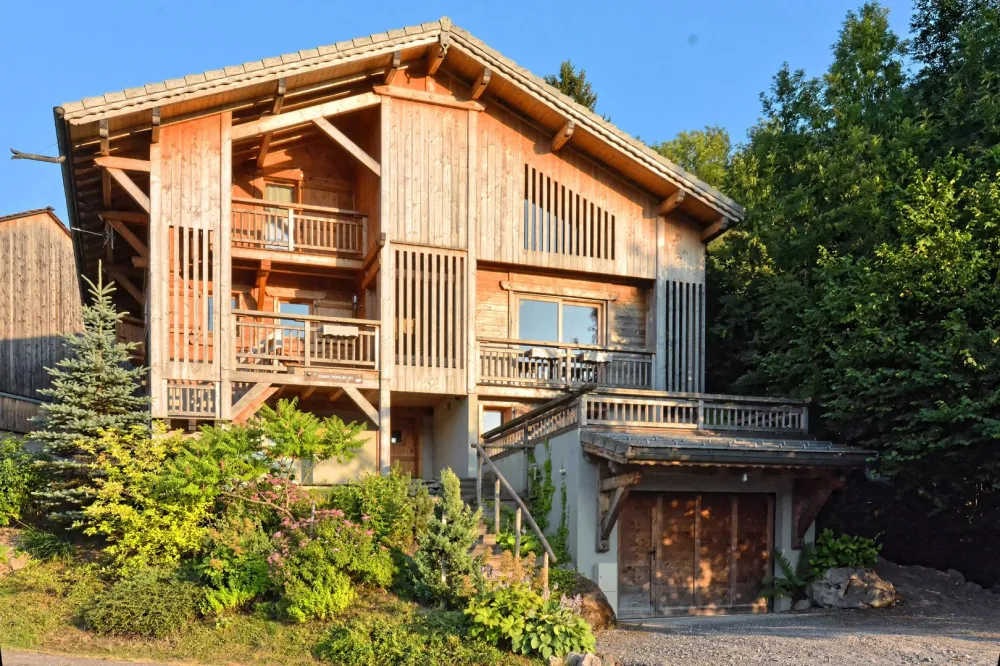 The chalet in summer at the sunset. View of the 3 levels of the chalet and the garage which contain a ski-boots dryer.