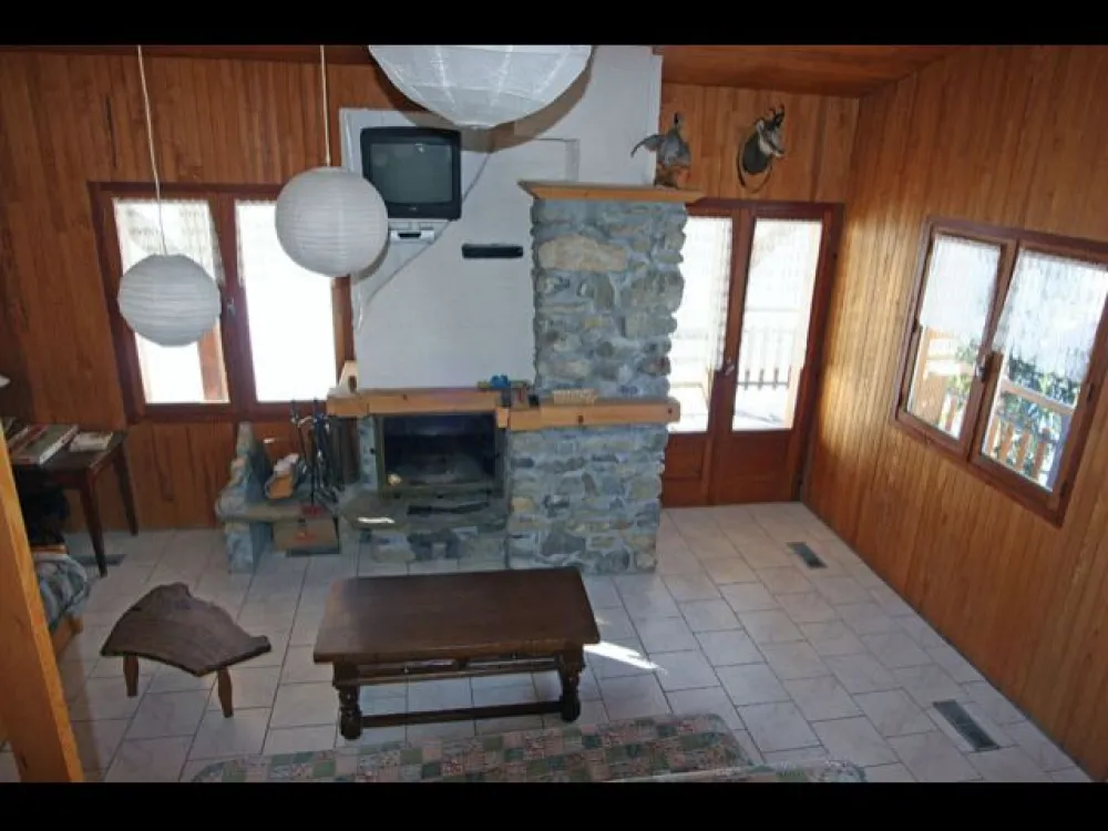 Salon de l'étage avec téléviseur et cheminée - 1 lit clic-clac et une banquette gigogne. 1 alcôve à claire-voie, avec un couchage et une table de nuit.  2 portes-fenêtres  donnant sur la terrasse et le balcon.