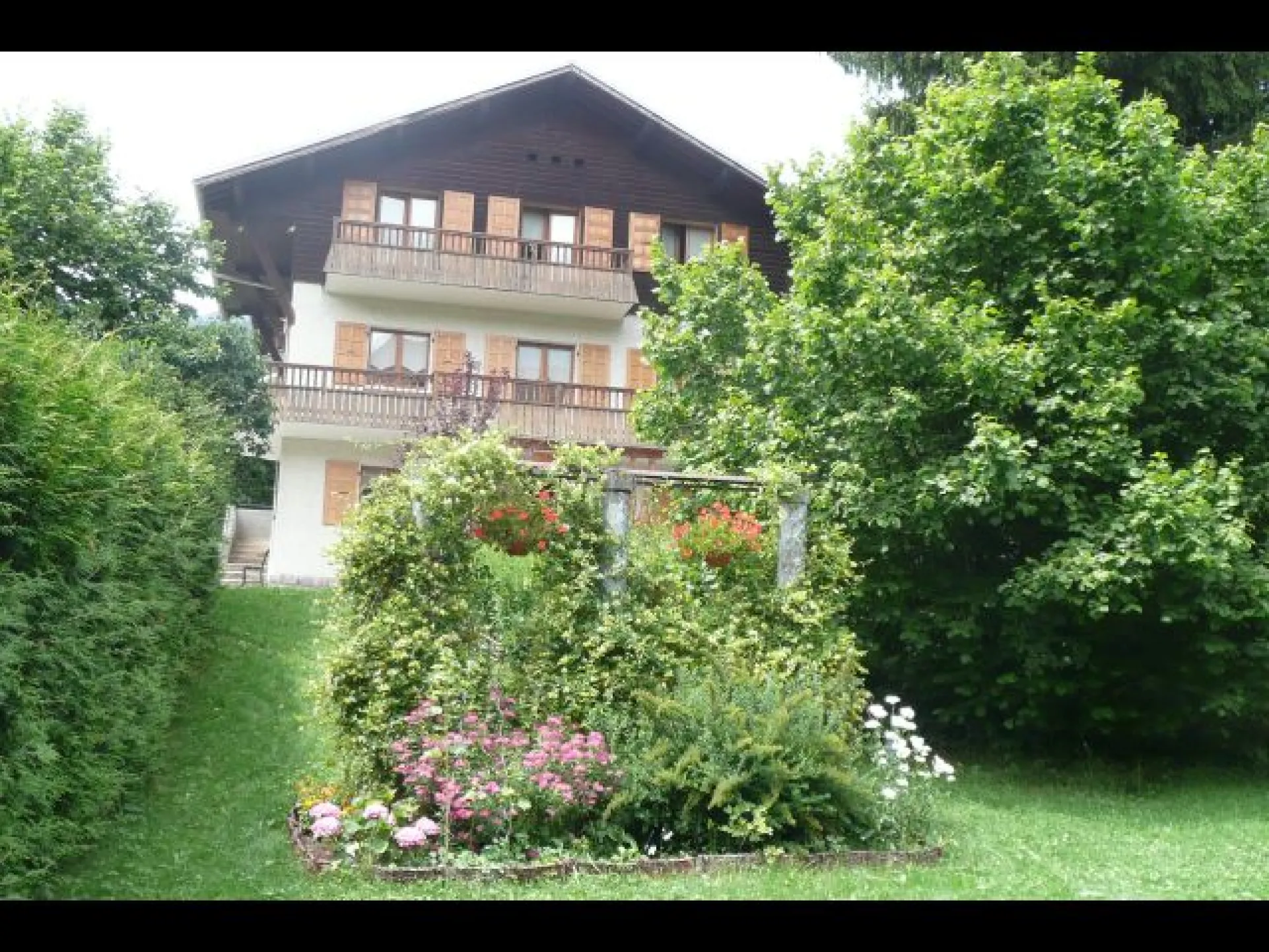 Le Chalet et son jardin durant l'été.
Le chalet comporte un garage fermé et plusieurs places de parking privées à son entrée.