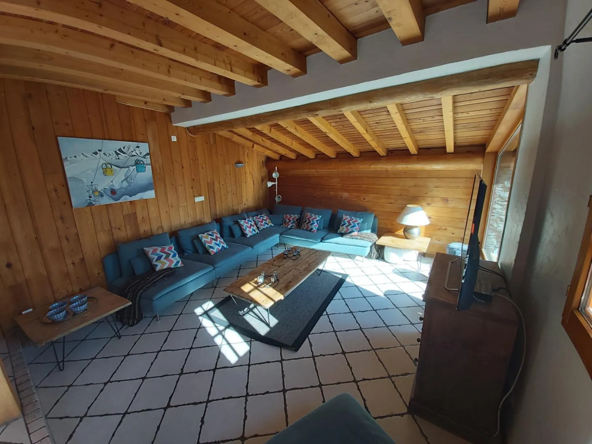 salon cosy équipé d'une grande télévision avec grande baie vue sur les montagnes