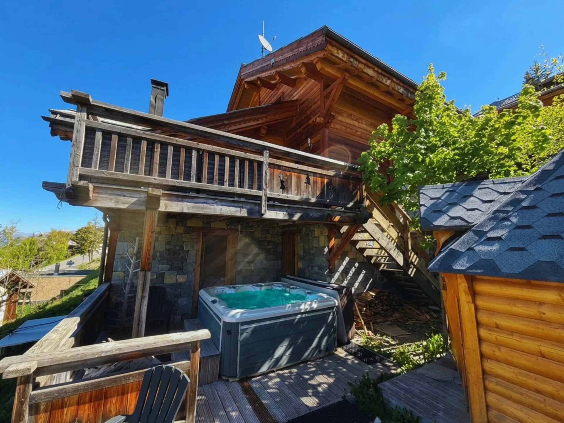L'espace extérieur du Chalet A : une grande terrasse aménagée et un espace bien-être complet avec jacuzzi et sauna face aux montagnes.