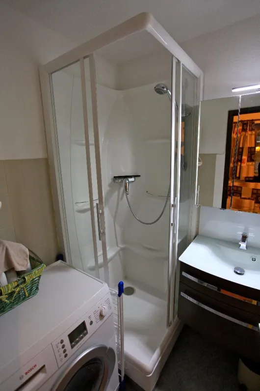 Salle de Douche avec cabine de douche, lavabo et machine à laver séchante. Les toilettes sont à part.