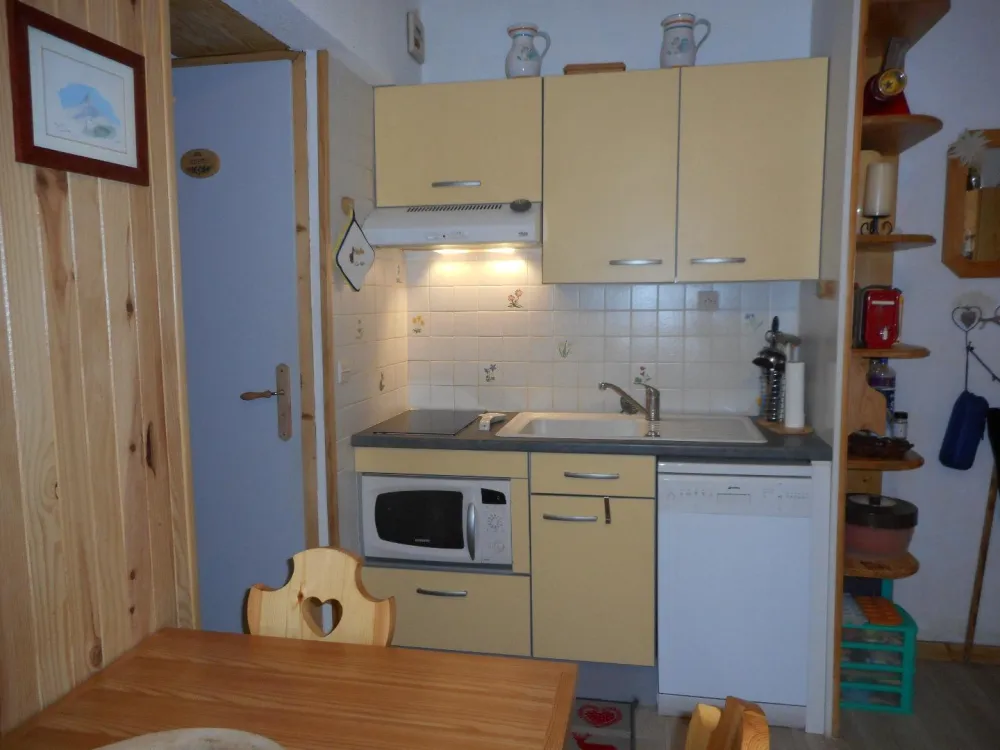 Coin cuisine équipée avec lave vaisselle, four combiné four à micro ondes, réfrigérateur, plaques vitrocéramiques. Fond de cuisine et vaisselle pour 4 personnes.