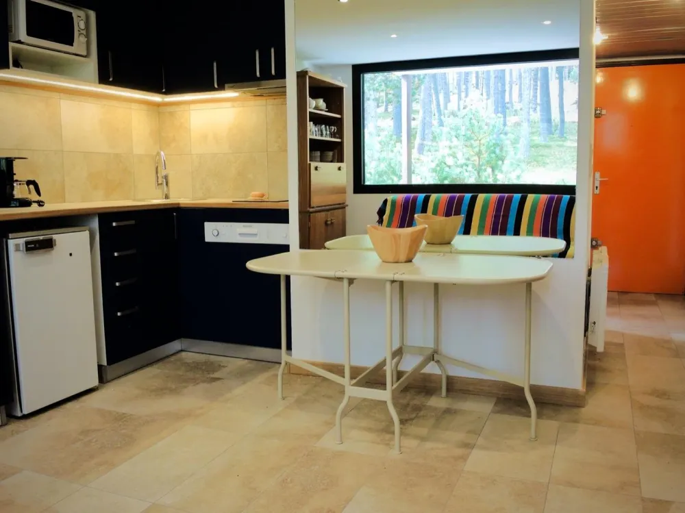 Kitchen and large mirror reflecting the forest.To the right, the corridor leading to the front door and the sleeping area.