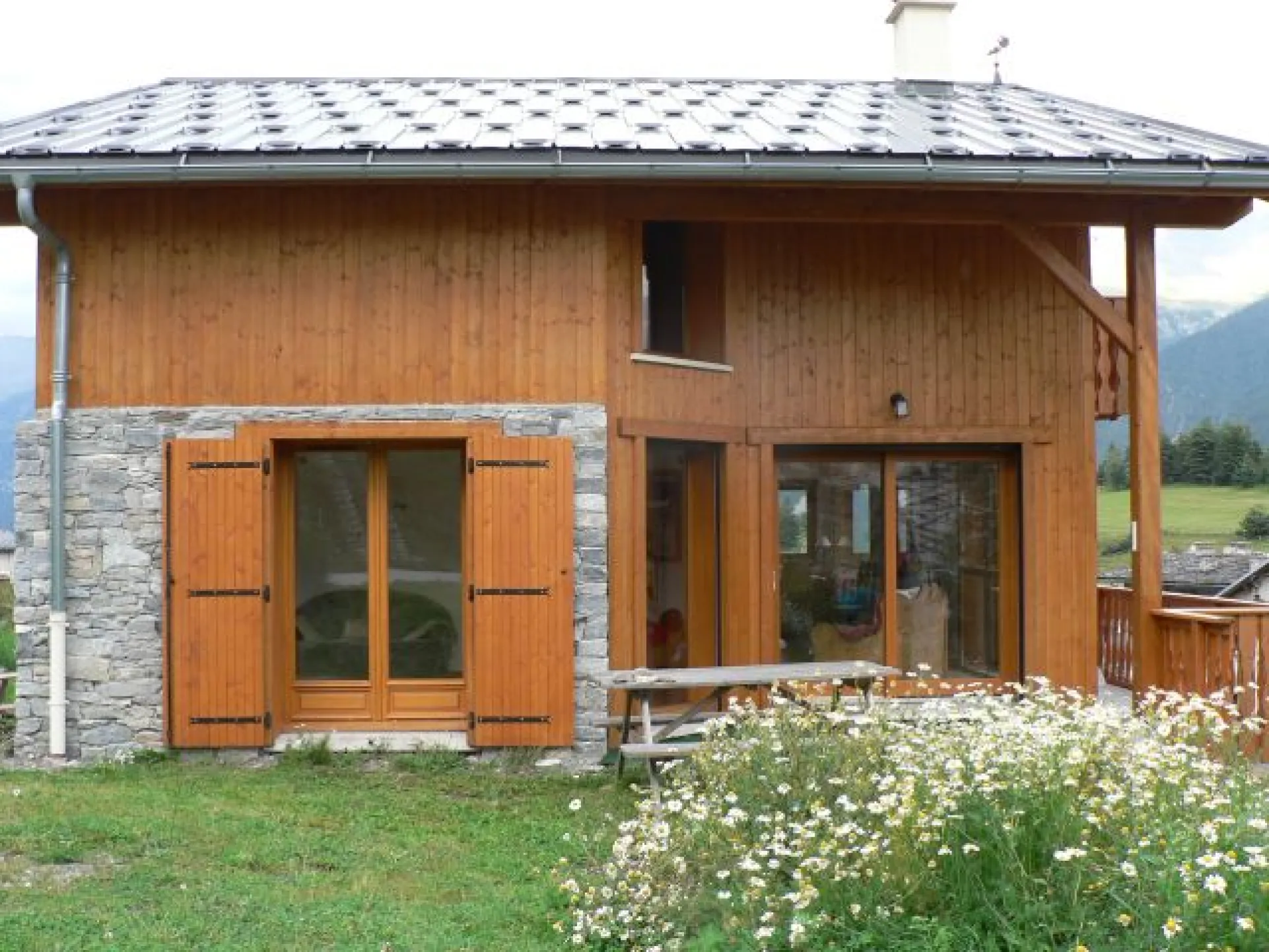 Chalet en été, terrasse à l'ouest, table et barbecue.
