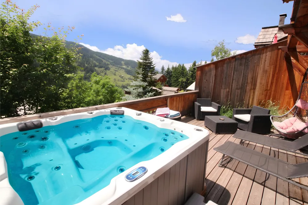 Jacuzzi extérieur privé chauffé à 37° toute l'année au RDC du Chalet B à Vars, installé sur une terrasse ensoleillée avec transats et fauteuils de relaxation.