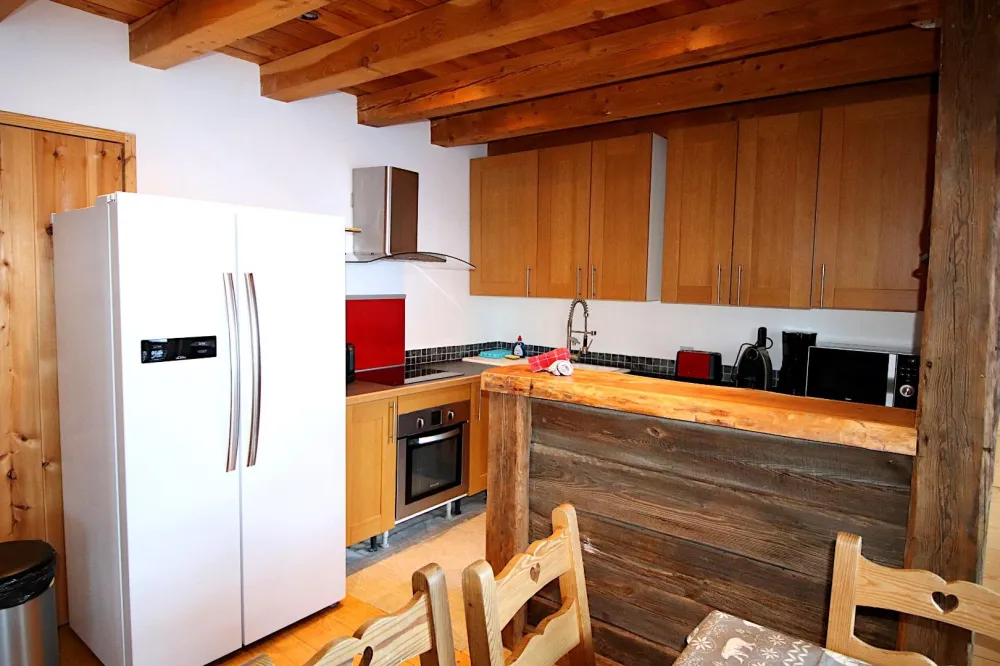 La cuisine toute équipée pour 12 personnes qui ouvre sur le salon. L'accès à la première terrasse se fait par la porte vitrée, où vous trouverez un salon de jardin avec table à manger, et le barbecue à charbon.