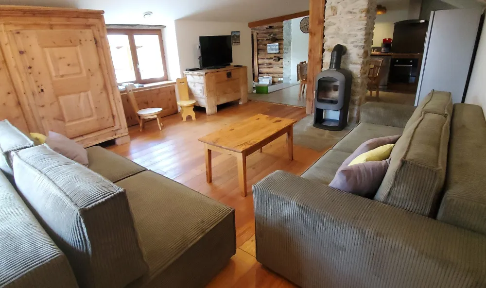 Le salon avec son poêle à bois et ses canapés confortables