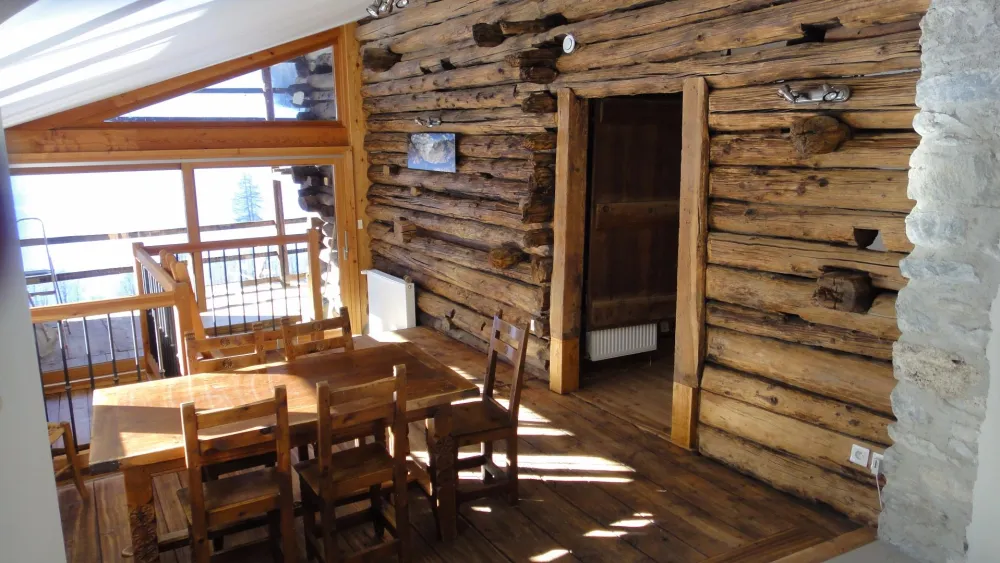 Le coin repas avec sa grande baie vitrée qui s'ouvre sur une terrasse couverte.