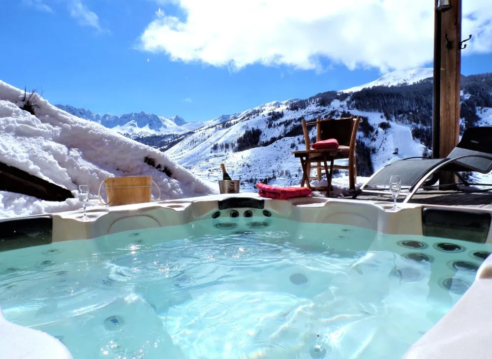 Jacuzzi extérieur 5 places du Chalet D à Vars, chauffé à 37°C toute l'année au milieu de la neige avec vue sur la montagne en hiver.