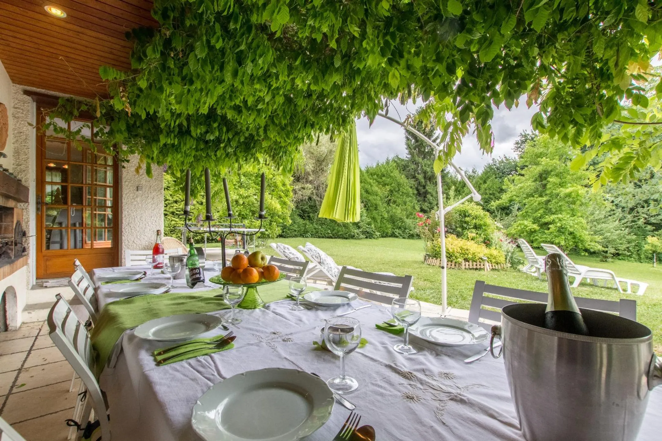 A large terrace shaded by wisteria opening onto the large garden