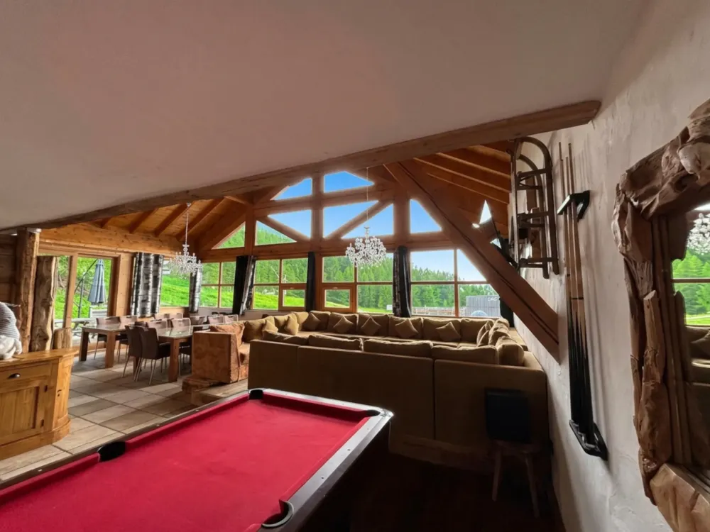 Grand canapé d'angle en U sous un toit cathédrale de 5m de hauteur, billard et salle à manger pour 22 personnes