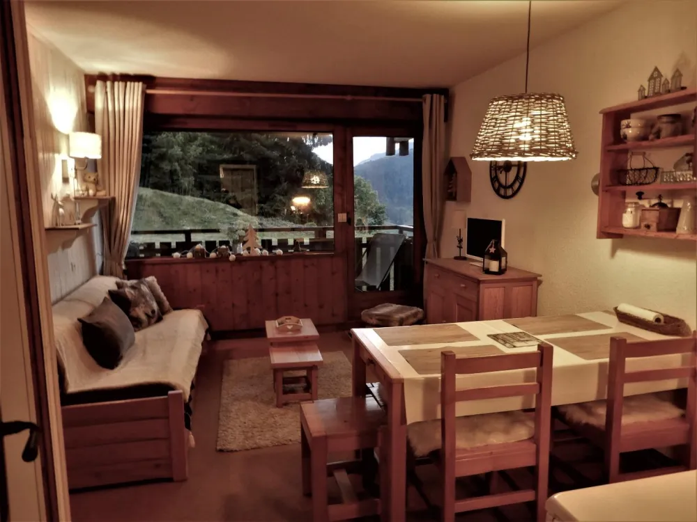 Appartement fonctionnel et chaleureux.
Le séjour en soirée, volets roulants électriques sur la baie vitrée et la porte donnant sur le balcon.