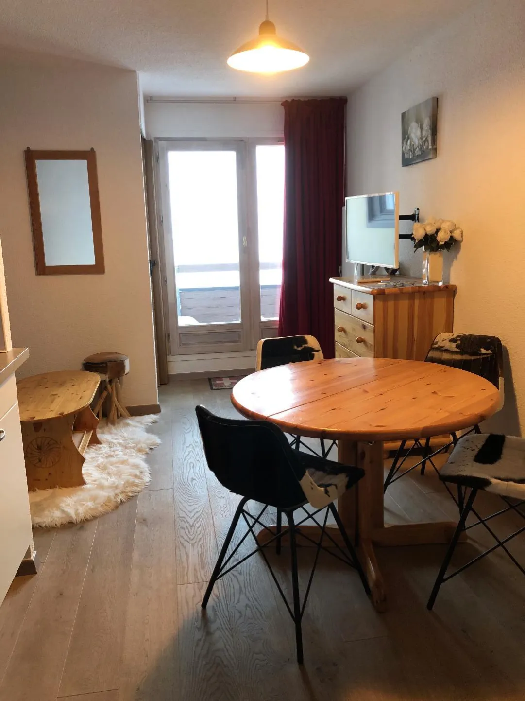 Séjour avec table et chaises , porte fenêtre avec vue sur les pistes de ski .