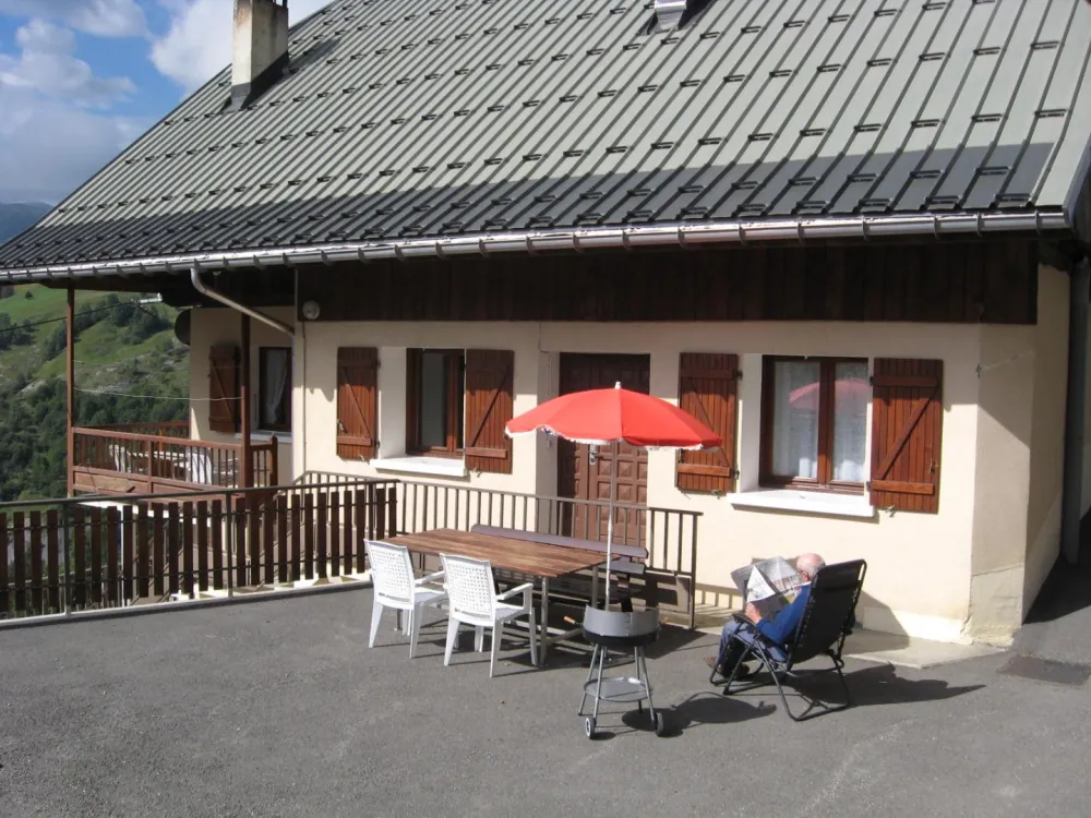 Devant l'appartement : table, parasol, chaises, barbecue...