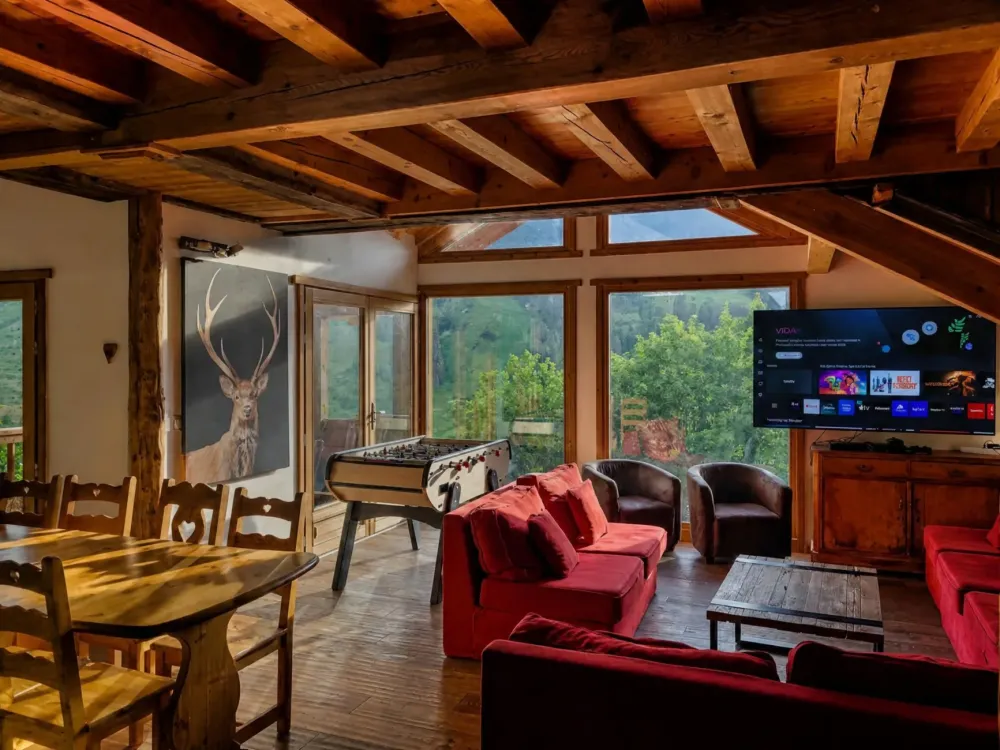Spacious living room in Chalet C in Vars, featuring a large corner sofa, a Smart TV, and a foosball table for family time.
