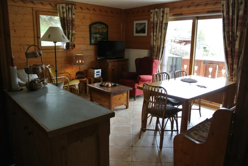 Pièce de vie vue de l'entrée de l'appartement.
A droite table banc et chaises du coin repas très confortable et spacieux
a gauche meuble plan de travail séparant le coin cuisine du séjour . Meuble accueillant une partie de la vaisselle
Baie vitrée  des
