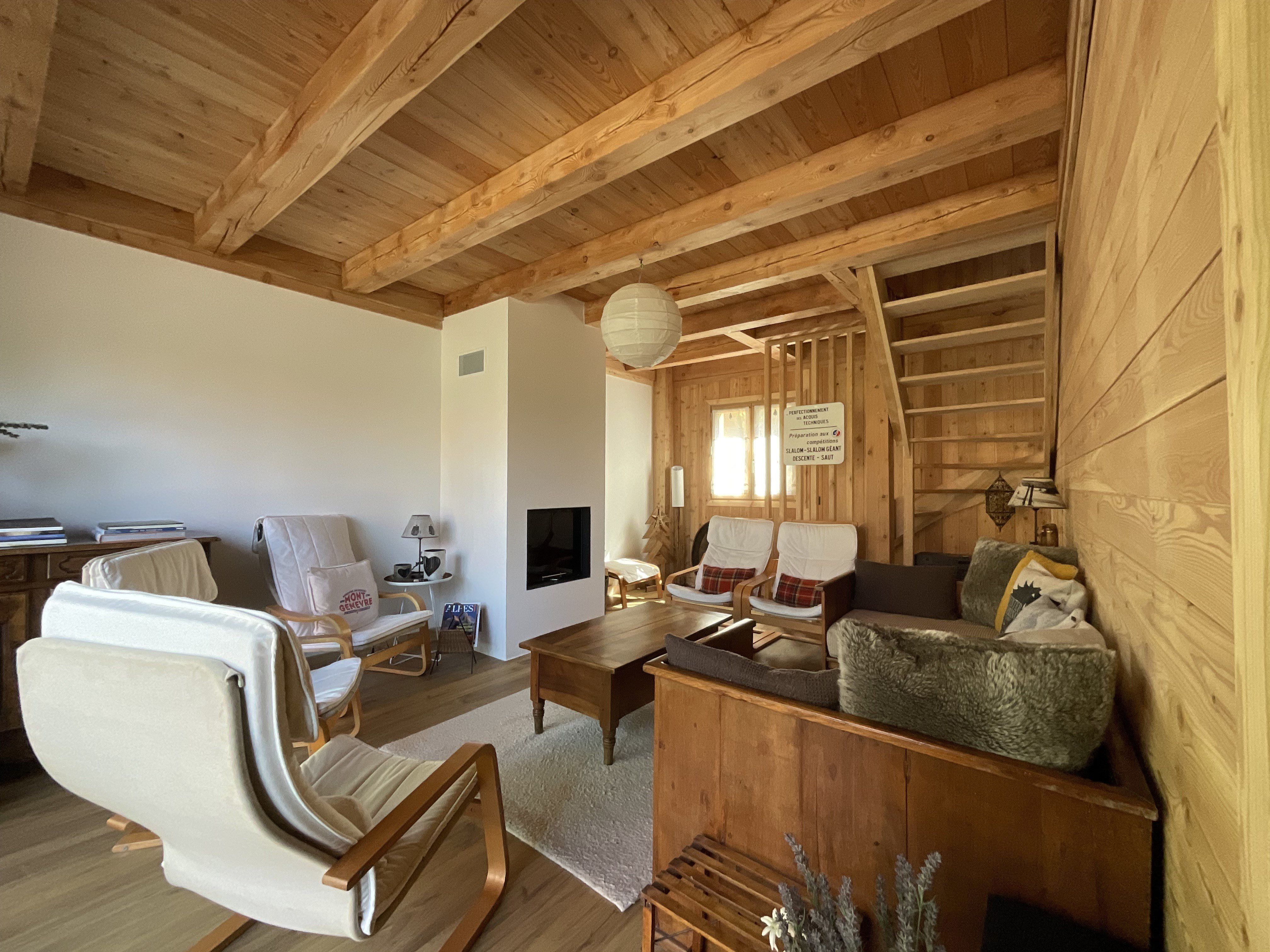 Un grand salon recouvert de mélèze doré comprenant 1 cheminée , 1 grande banquette en bois, 5 fauteuils comfortables, 1 table basse et 1 buffet, le tout ouvrant sur la terrasse 