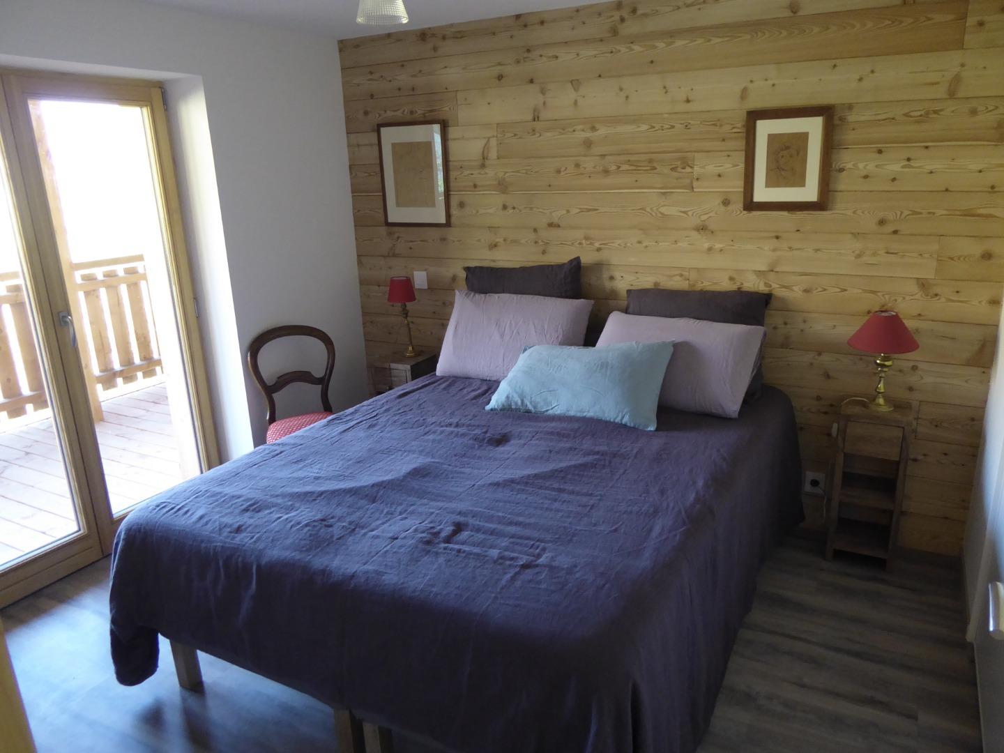 chambre mitoyenne du séjour avec sa porte-fenêtre sur la terrasse et la vue sur les montagnes