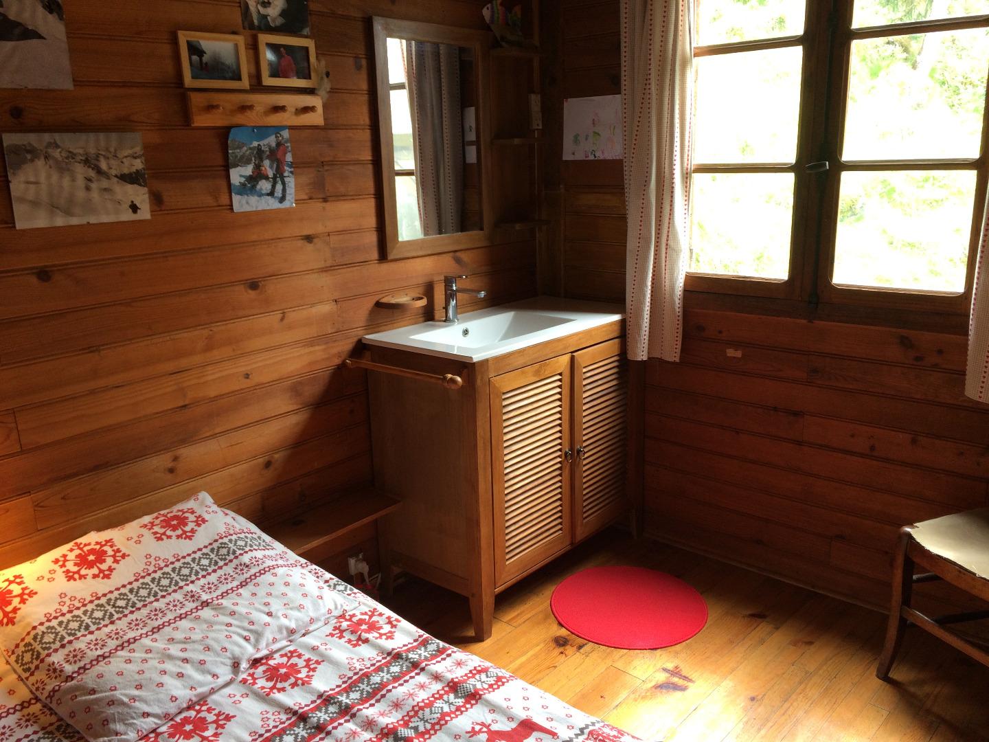 Chambre 1 en RDC avec son lit double et son coin lavabo