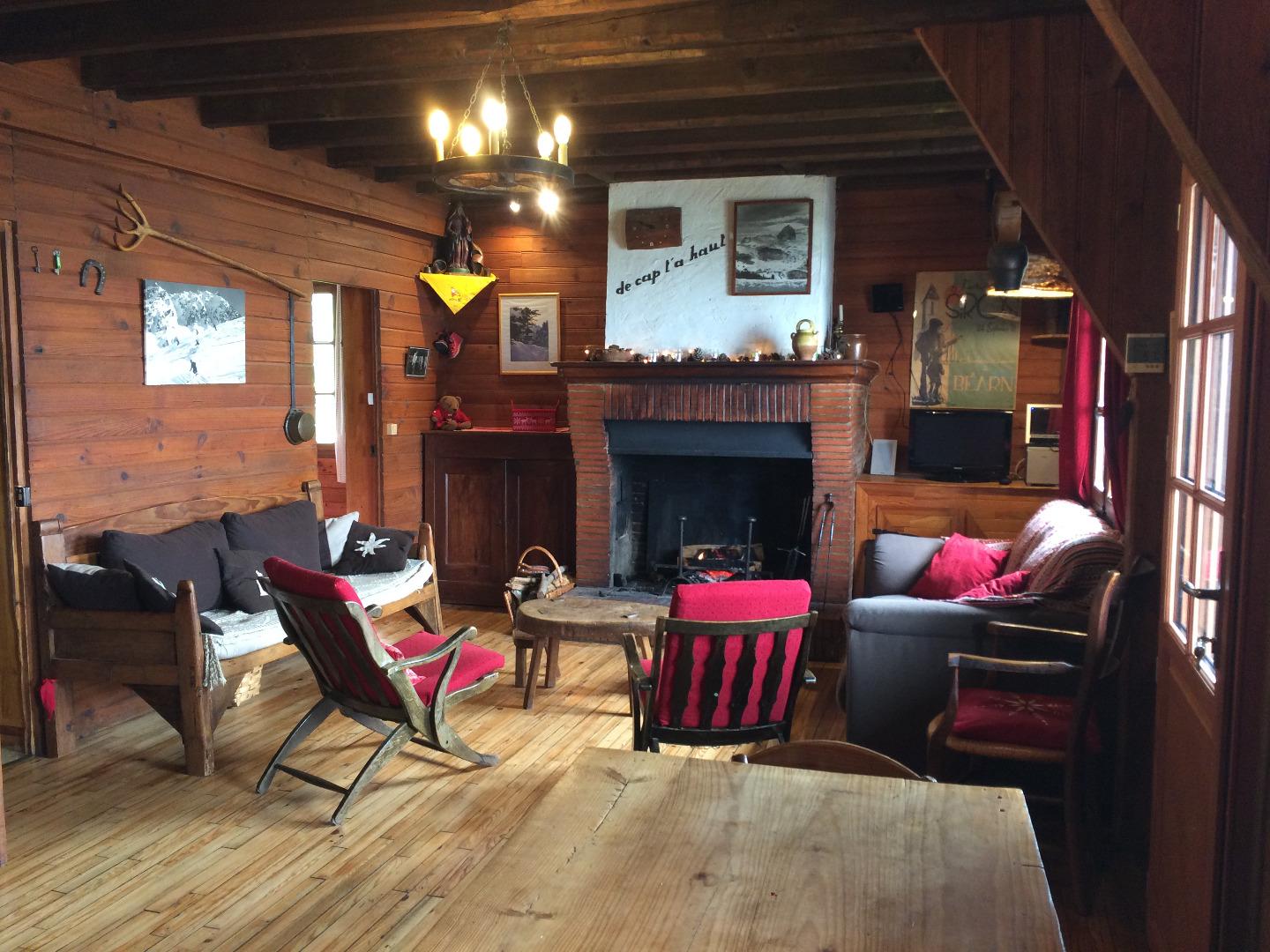 Pièce principale avec le coin salon autour de la cheminée,la grande table et les bancs coté salle à manger.