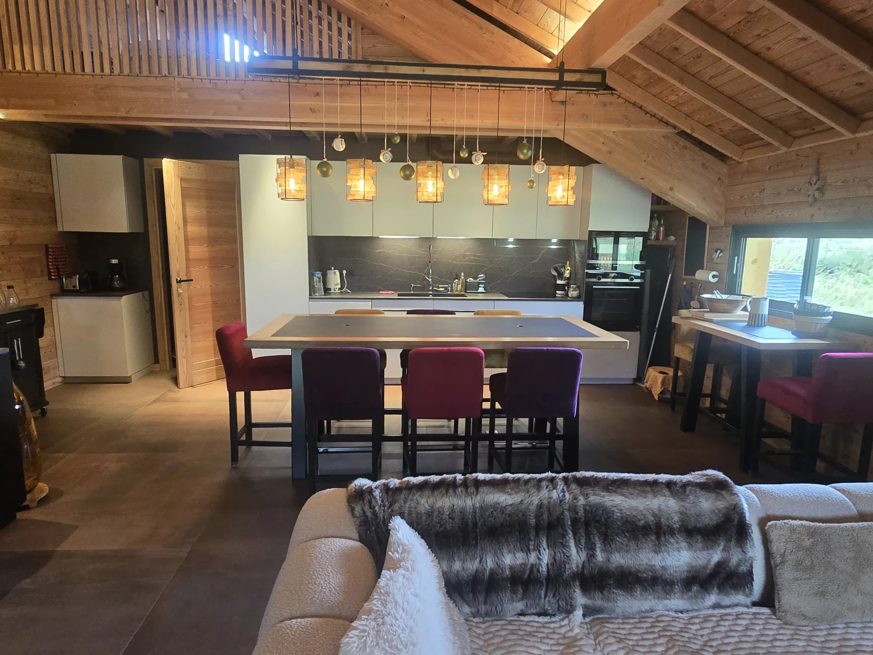 Vue de la table depuis le salon. La table est notamment équipée pour les raclettes (prises au sol).