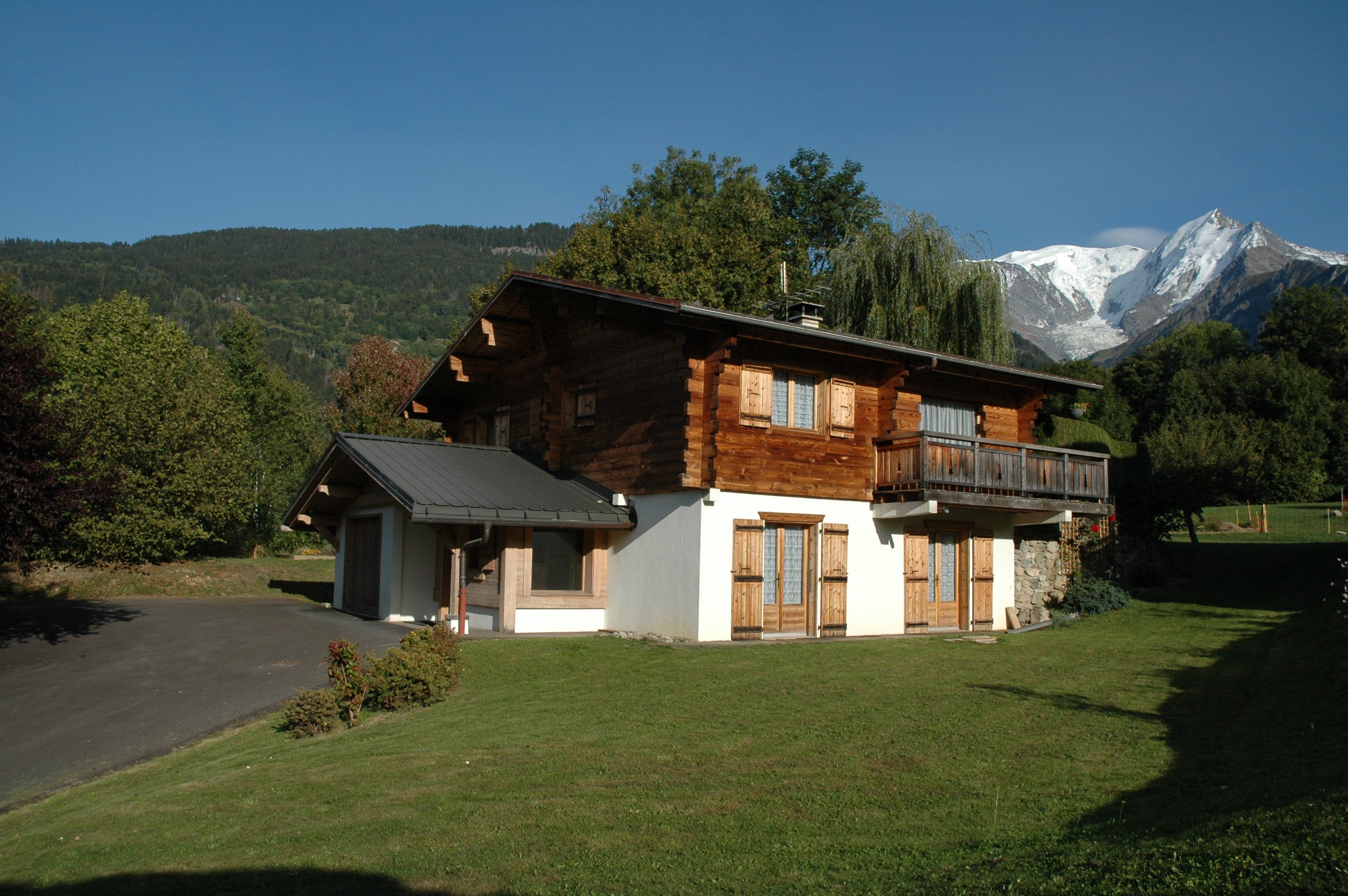 Le chalet dans son cadre de verdure et la vue sur le massif du Mont Blanc