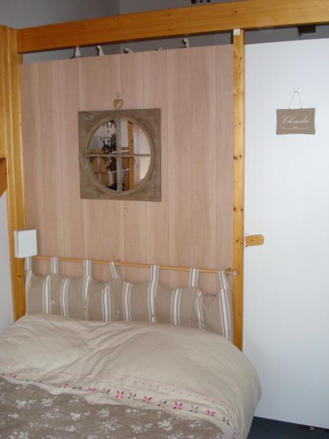 Vue de la 2e chambre, donnant sur le séjour, comprenant un lit 2 places, un bureau, une télé à écran plat.