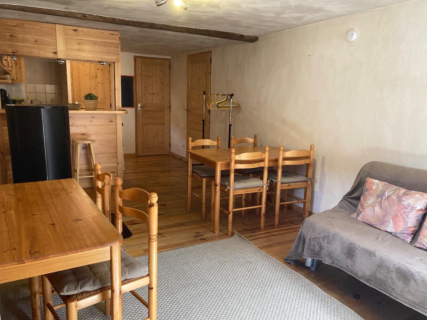 vue sur l'ensemble de la pièce à vivre avec la porte d'entrée de l'appartement au fond à droite et la porte de la salle de douche au fond. 
