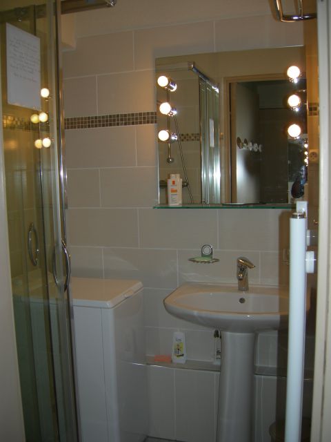 salle de bain carrelée, avec machine à laver ef cabine de douche.