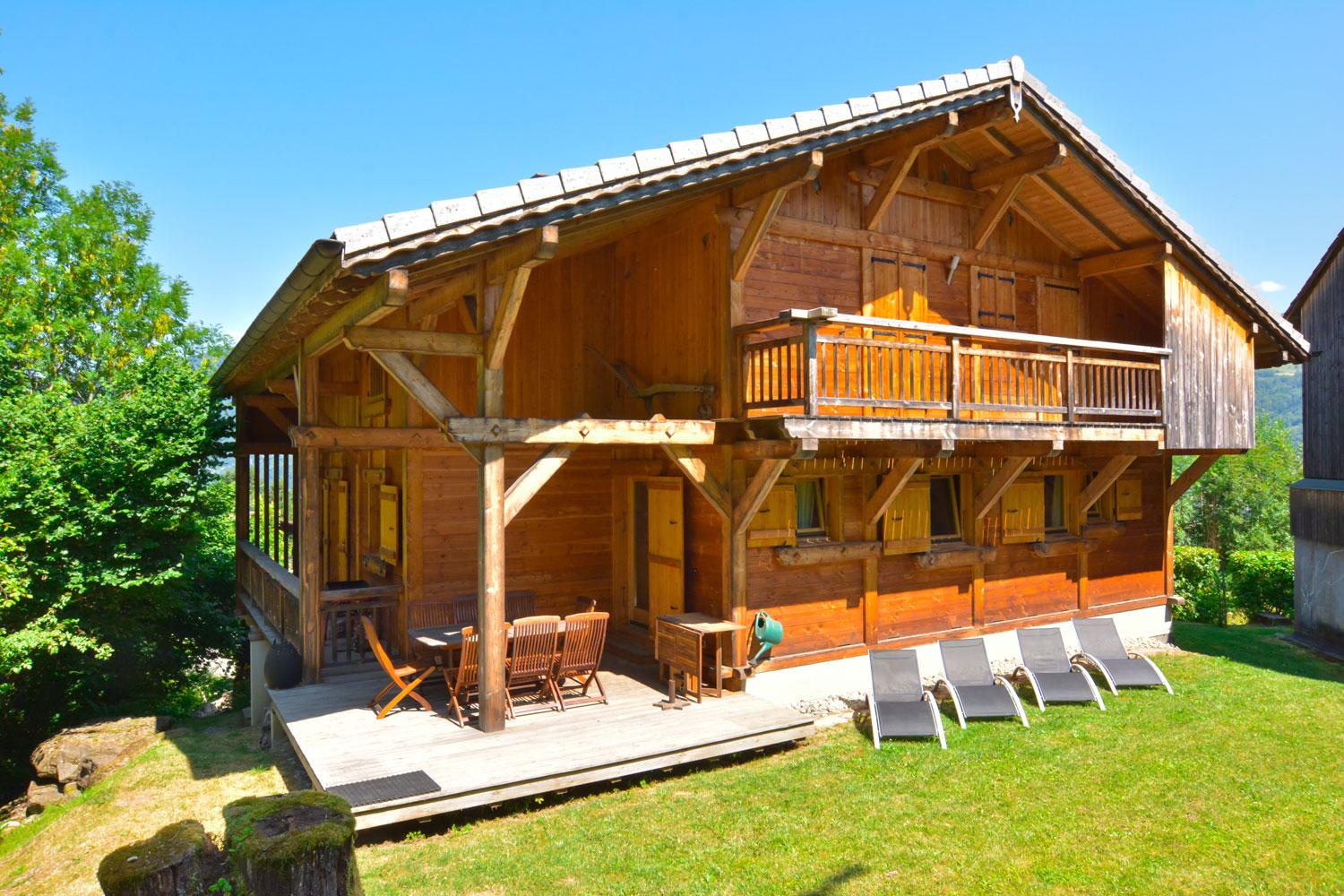 Le chalet en été côté Sud. La terrasse avec son équipement pour les repas. En bordure du ruisseau. 