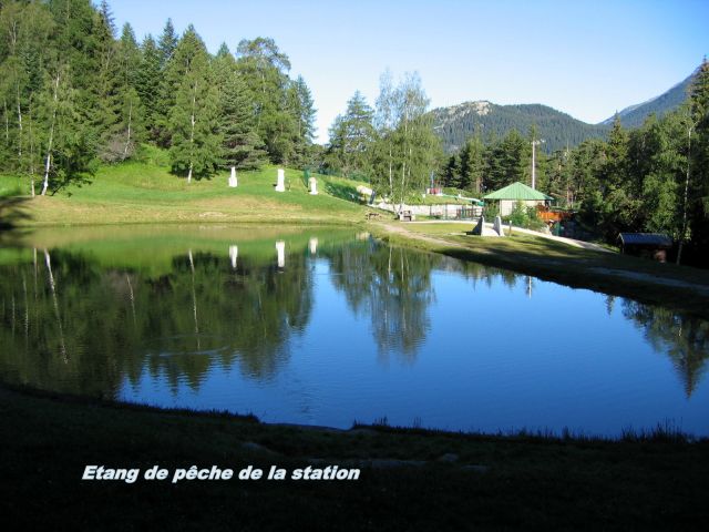 l'Etang de pêche de la station, avec les aménagement table banc et grille barbecue, pêche à la truite, carte disponible à l'office du tourisme de la station, à l'arrière la piscine de plein air surveillé en saison,