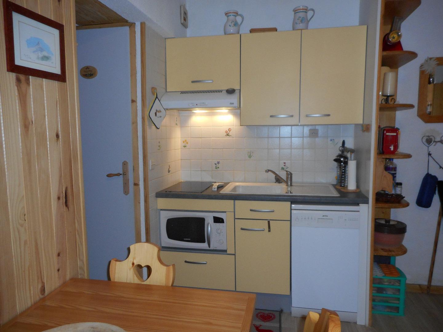 Coin cuisine équipée avec lave vaisselle, four combiné four à micro ondes, réfrigérateur, plaques vitrocéramiques. Fond de cuisine et vaisselle pour 4 personnes.