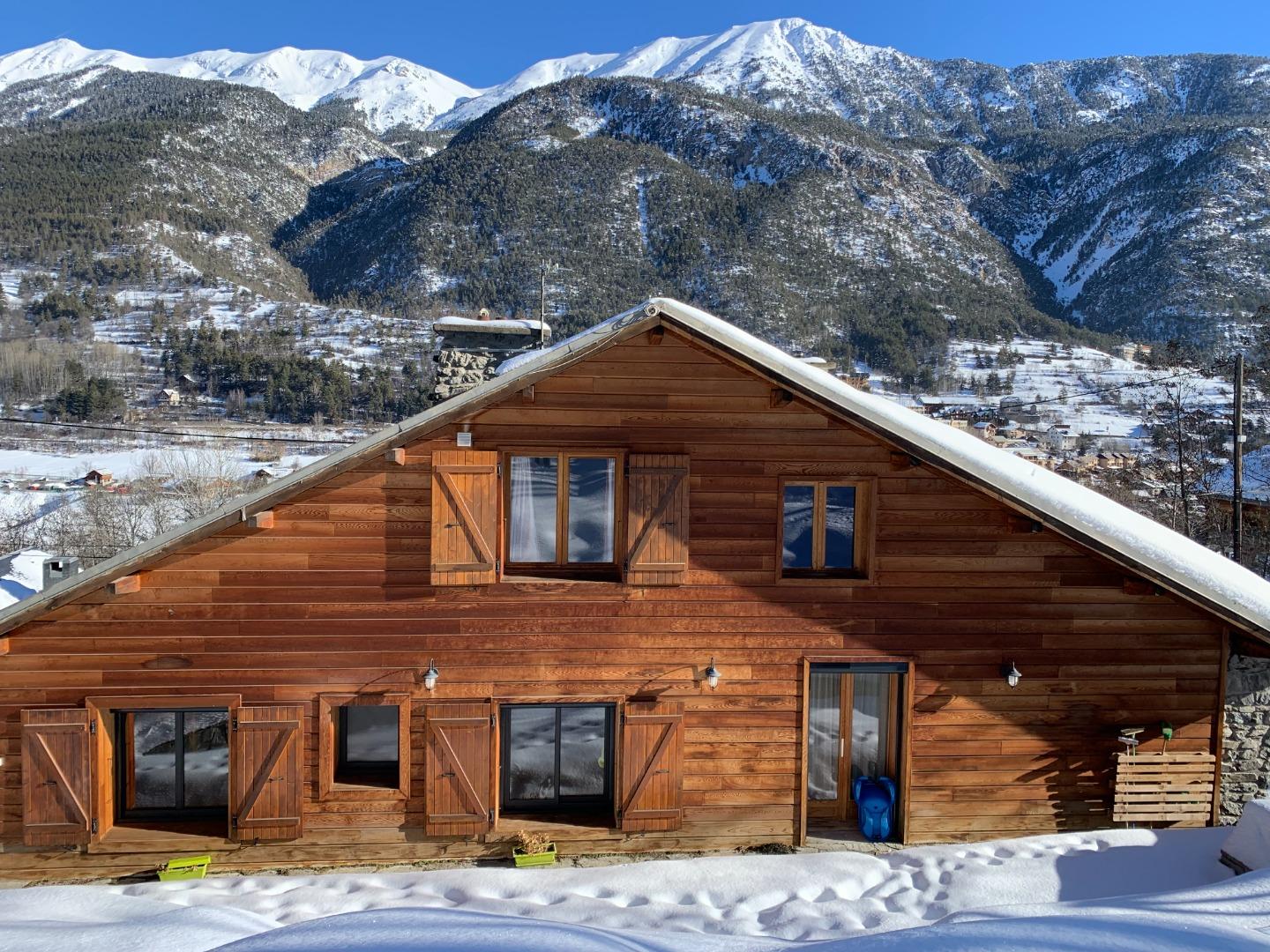 Face au chalet, les crêtes de Peyrolle et le Grand Aréa se dessinent sous la neige, sommets qui changent de lumière au fil de la journée. Chalet Mont Milo, 160 m² en pierre et bois, à 5 minutes des pistes de Serre Chevalier Vallée.