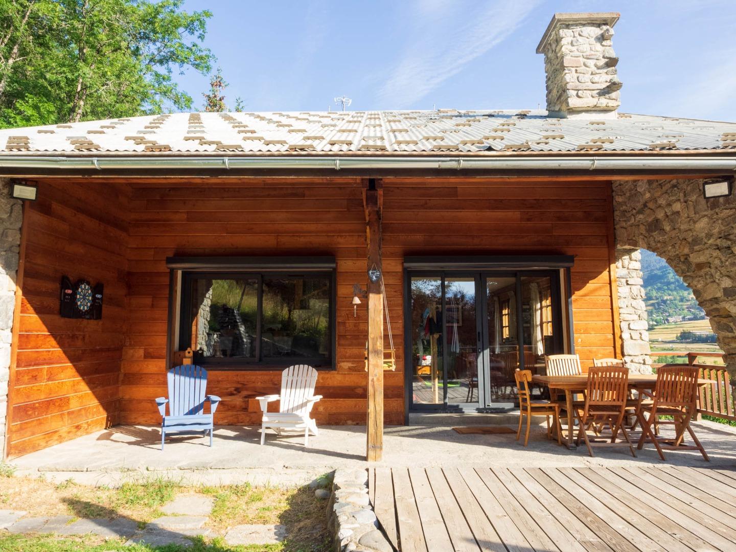 La terrasse extérieure du Chalet Mont Milo s'ouvre sur la vallée, table dressée pour les repas d'été et transats pour prolonger la journée au soleil. Un espace qui prend vie dès les premiers beaux jours.