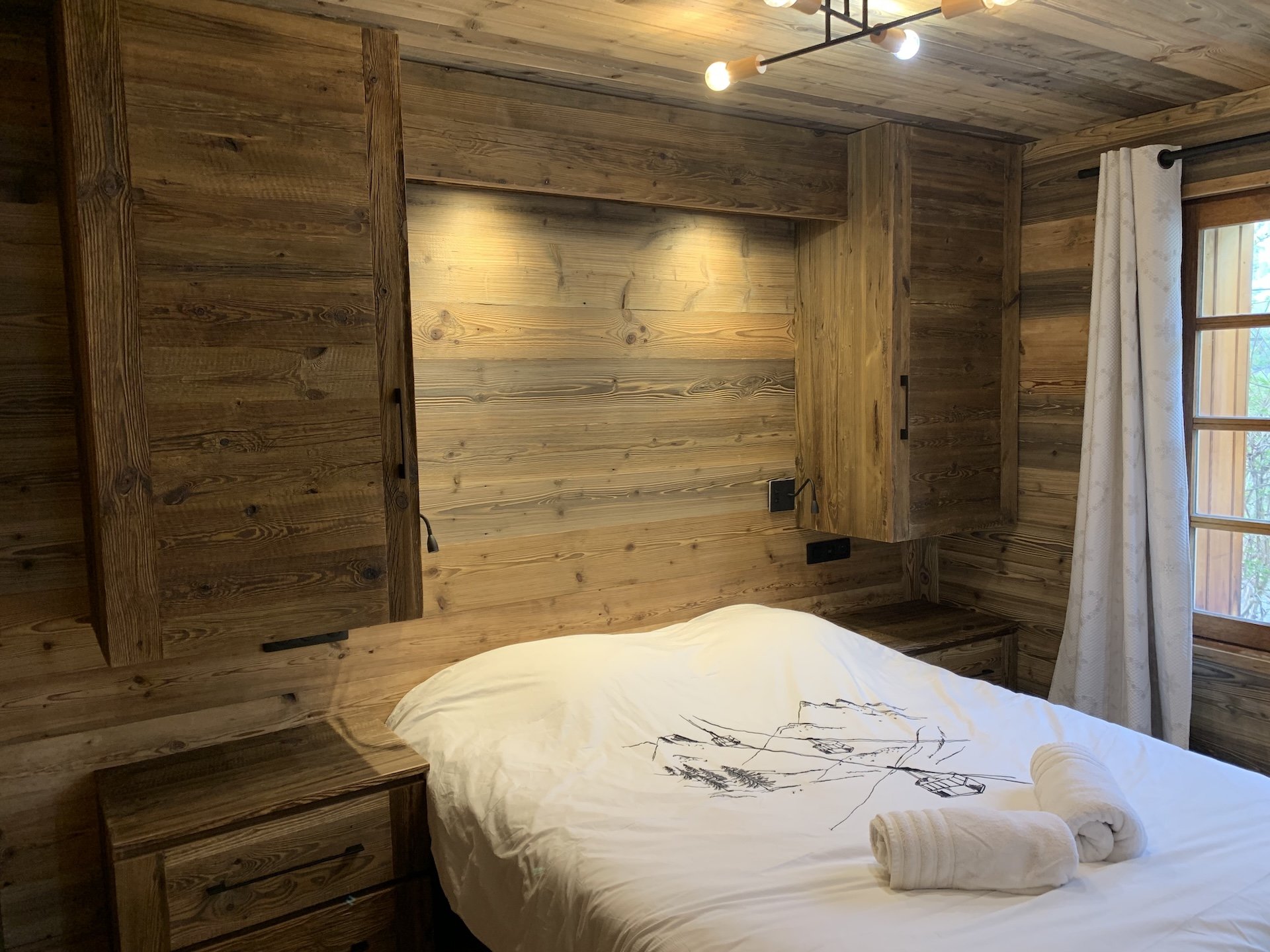 Chalet Mont-Milo : Chambre Grand Aréa rénovée en 2026. Vue vallée & montagnes, lit 160x200, literie neuve, vieux bois authentique, éclairage tamisé, rangements intégrés. Cocon idéal après vos journées en montagne