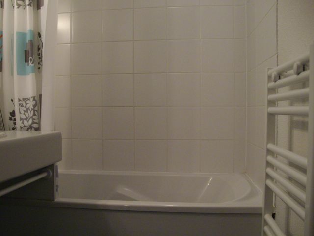 Salle de bain avec baignoire, lavabo et radiateur sèche serviettes